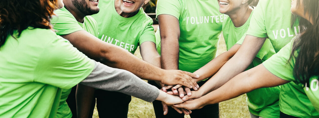 Group of nonprofit volunteer people stacking hands celebrating together - Charity green environmental project and teamwork concept